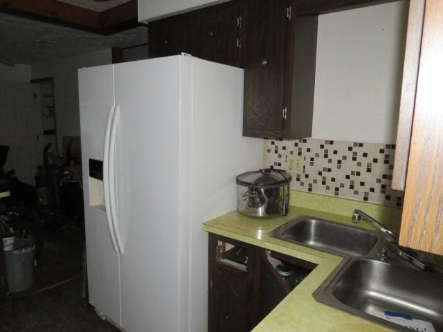 kitchen with backsplash, white fridge with ice dispenser, dark brown cabinets, and sink