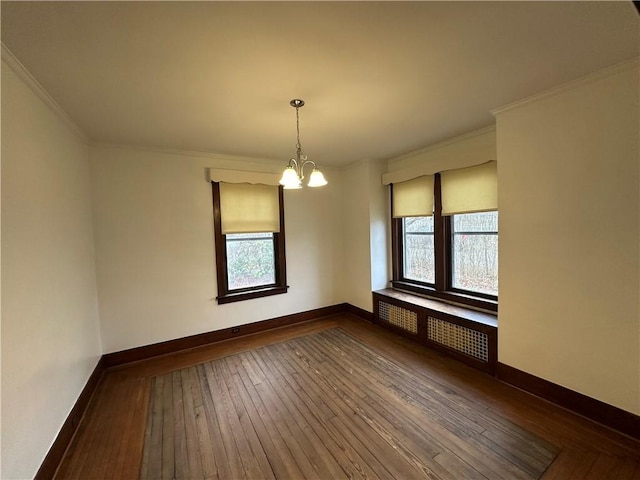 empty room featuring radiator heating unit, crown molding, hardwood / wood-style floors, and a notable chandelier