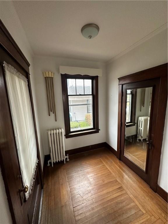 unfurnished room with radiator, wood-type flooring, and ornamental molding