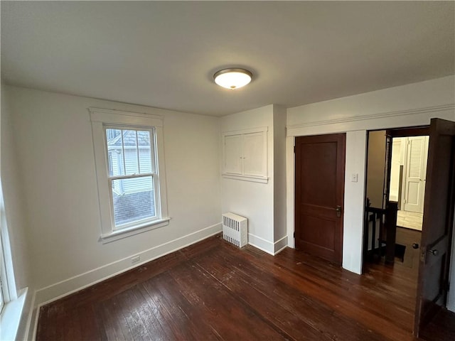 unfurnished bedroom with dark wood-type flooring, radiator heating unit, and a closet