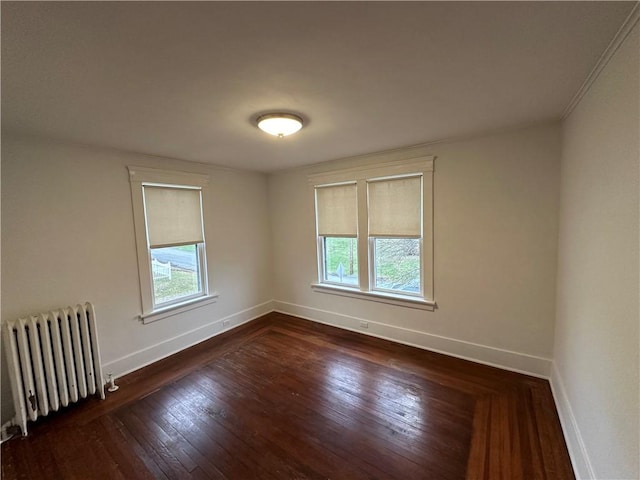 unfurnished room featuring a healthy amount of sunlight, radiator, and dark hardwood / wood-style floors