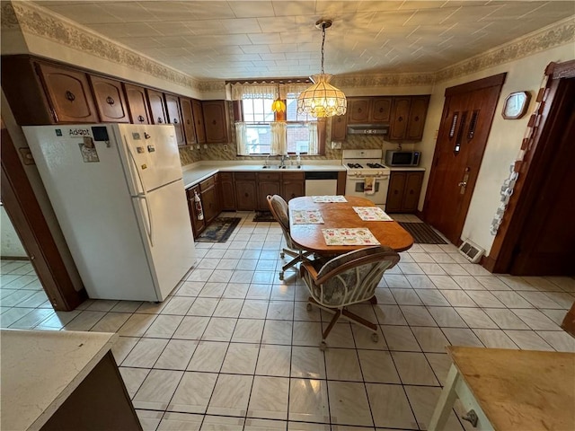 kitchen featuring white appliances, light tile patterned floors, light countertops, under cabinet range hood, and a sink