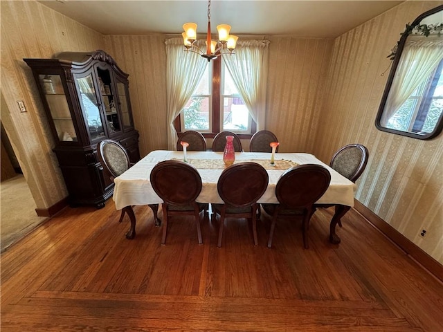 dining space featuring a notable chandelier, wooden walls, and wood finished floors