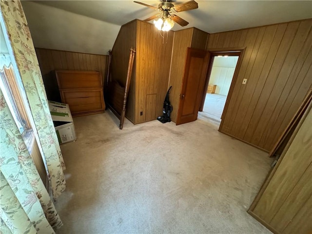 additional living space with light carpet, wooden walls, ceiling fan, and vaulted ceiling