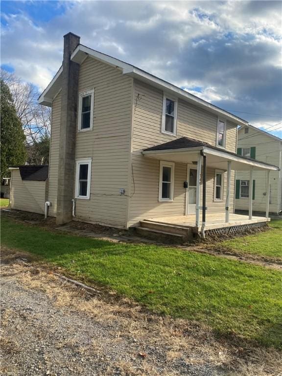 rear view of property featuring covered porch and a lawn