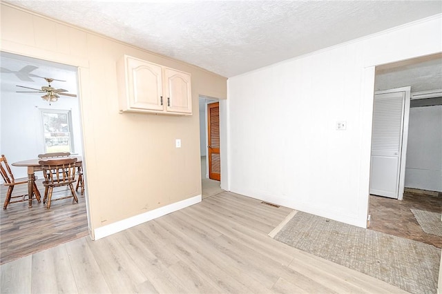 spare room with ceiling fan, a textured ceiling, and light hardwood / wood-style flooring