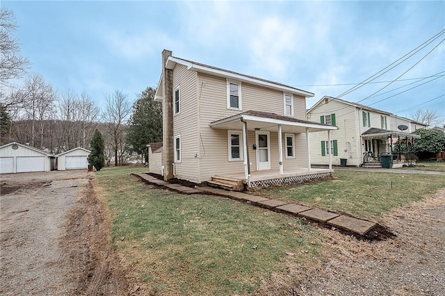 front facade featuring an outbuilding, a porch, a garage, and a front yard