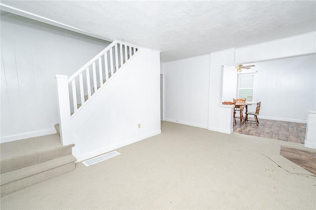 basement with carpet flooring, ceiling fan, and a textured ceiling