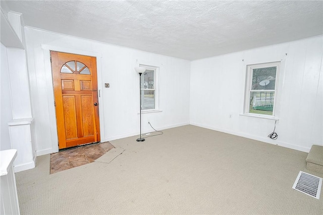 foyer with light colored carpet and a textured ceiling