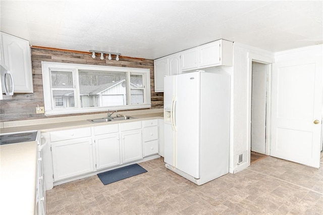 kitchen featuring stove, white cabinets, sink, rail lighting, and white fridge with ice dispenser