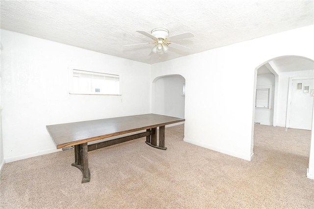 unfurnished office with ceiling fan, light colored carpet, and a textured ceiling