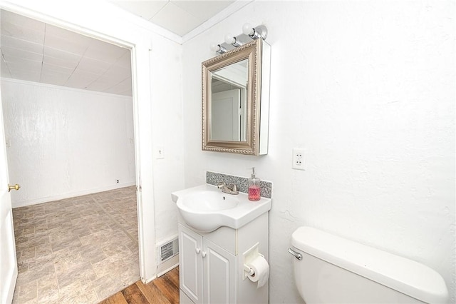 bathroom with crown molding, vanity, and toilet