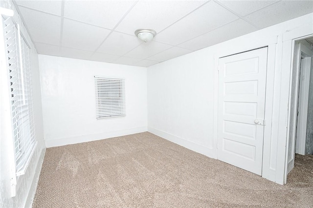 carpeted empty room featuring a drop ceiling