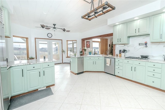 kitchen with kitchen peninsula, backsplash, stainless steel appliances, and green cabinetry