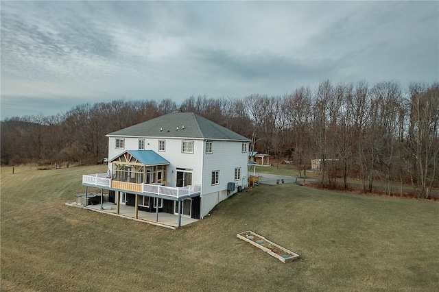 rear view of property featuring a lawn, a sunroom, a patio, and a deck