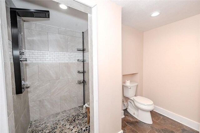 bathroom featuring a tile shower and toilet