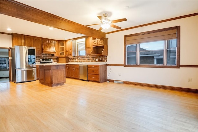 kitchen with ceiling fan, a center island, tasteful backsplash, light hardwood / wood-style flooring, and appliances with stainless steel finishes