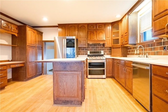 kitchen with sink, backsplash, appliances with stainless steel finishes, a kitchen island, and light wood-type flooring