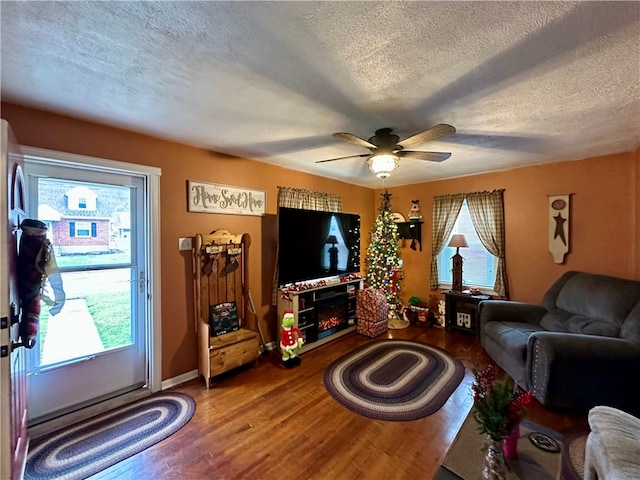 living room with a textured ceiling, ceiling fan, and wood-type flooring