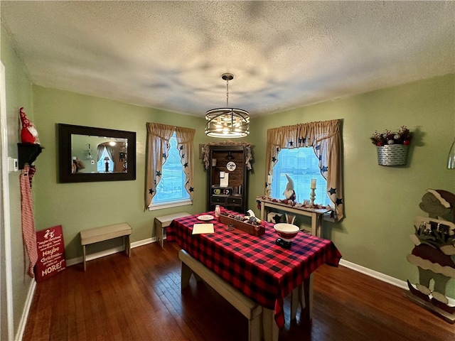 dining space with a textured ceiling, dark hardwood / wood-style floors, and a notable chandelier