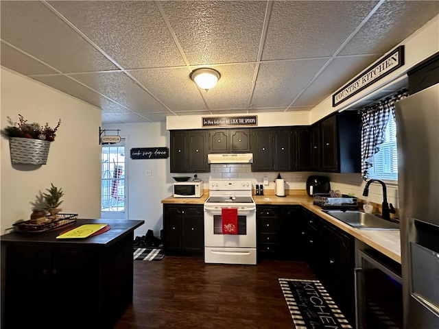 kitchen featuring tasteful backsplash, a drop ceiling, sink, white appliances, and dark hardwood / wood-style flooring