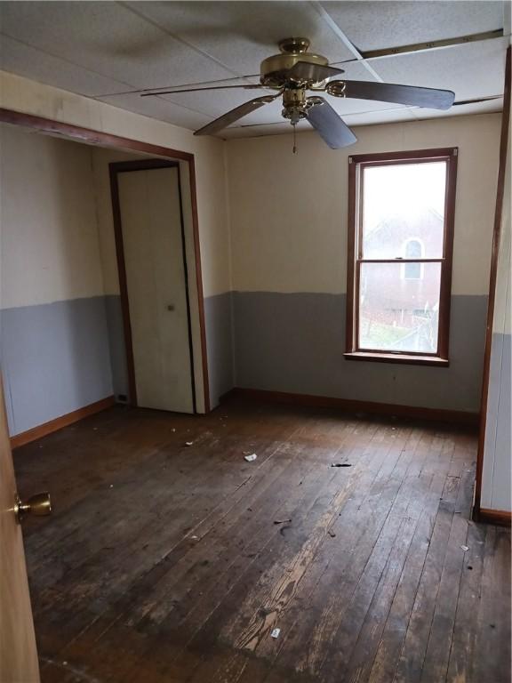 empty room featuring dark hardwood / wood-style flooring, ceiling fan, and a paneled ceiling