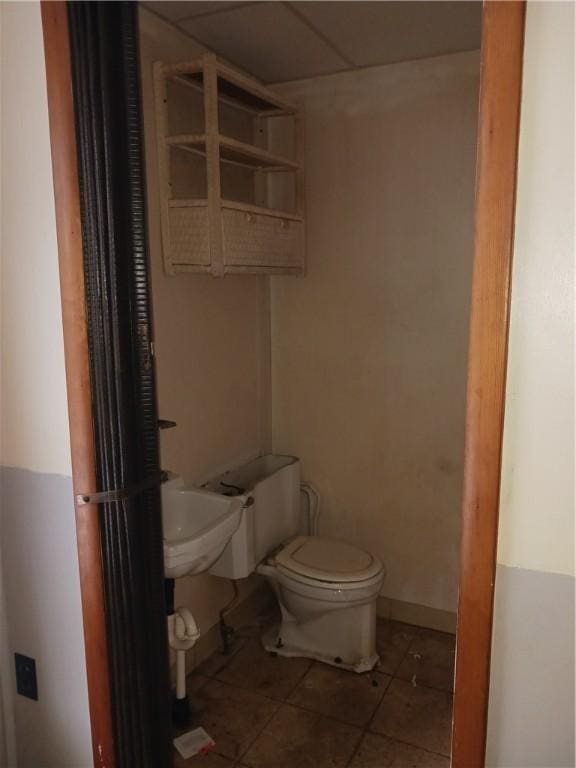 bathroom featuring tile patterned floors, a drop ceiling, and toilet