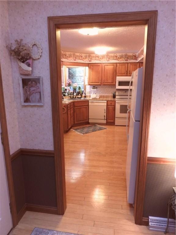 kitchen with light hardwood / wood-style floors, white appliances, and sink