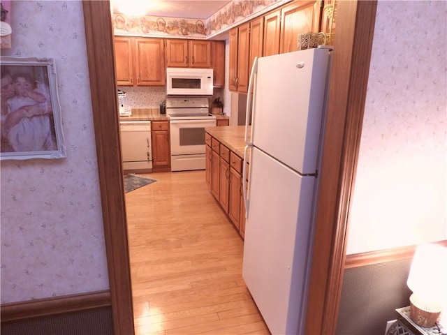 kitchen featuring white appliances and light hardwood / wood-style flooring