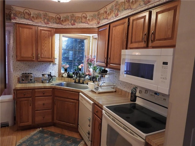 kitchen with light hardwood / wood-style floors, white appliances, and sink