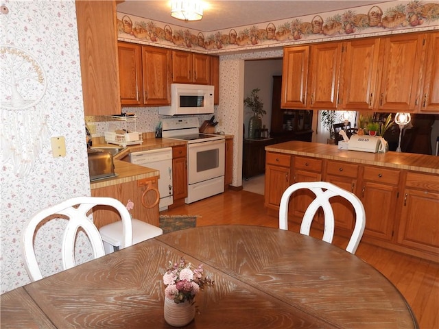 kitchen with sink, white appliances, and light wood-type flooring