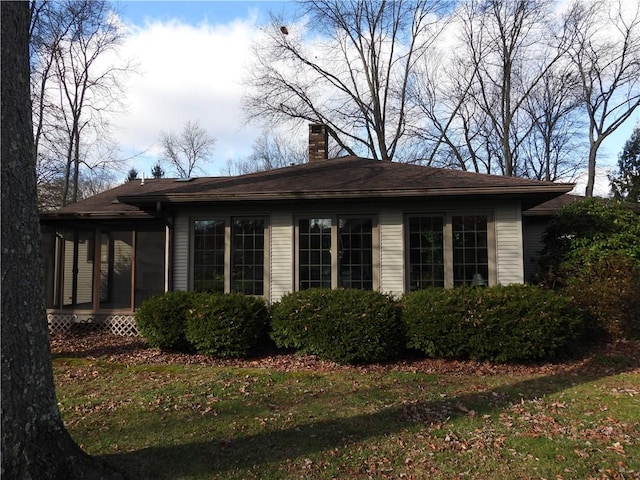 view of home's exterior with a yard and a sunroom