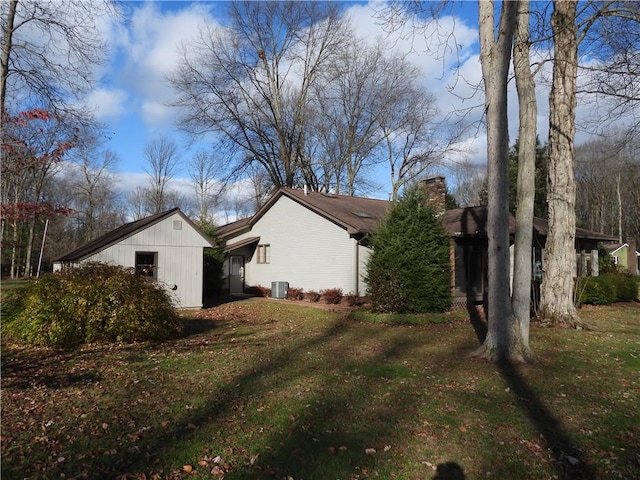 view of side of property featuring cooling unit and a lawn