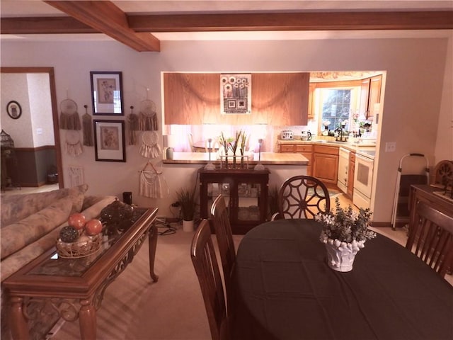 dining room featuring beamed ceiling and light carpet