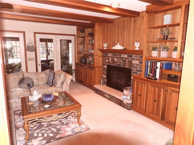 carpeted living room with wood walls, a fireplace, and beamed ceiling