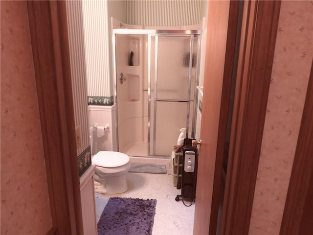 bathroom with toilet and a shower with door