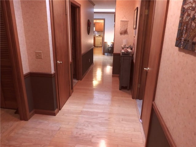 hallway with light hardwood / wood-style flooring and ornamental molding