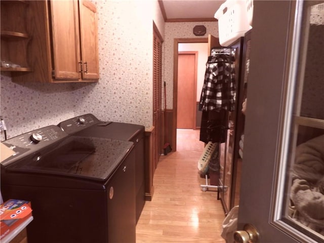 kitchen with washing machine and clothes dryer, crown molding, and light wood-type flooring