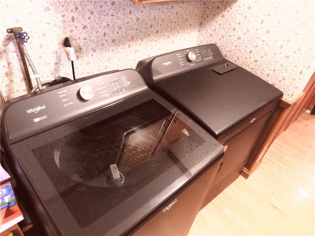 laundry area with washer and clothes dryer and light hardwood / wood-style floors