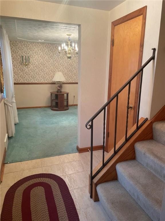 staircase with carpet floors, wallpapered walls, an inviting chandelier, baseboards, and tile patterned floors