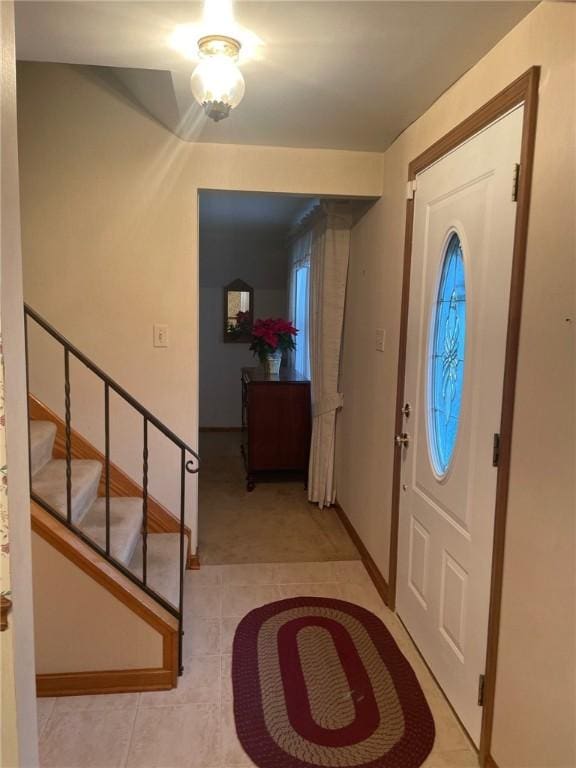 foyer entrance with stairs, light tile patterned floors, and baseboards