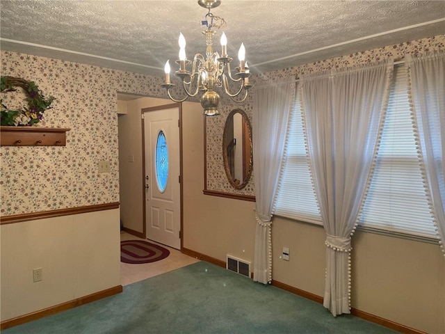 entrance foyer featuring carpet, a textured ceiling, and a notable chandelier