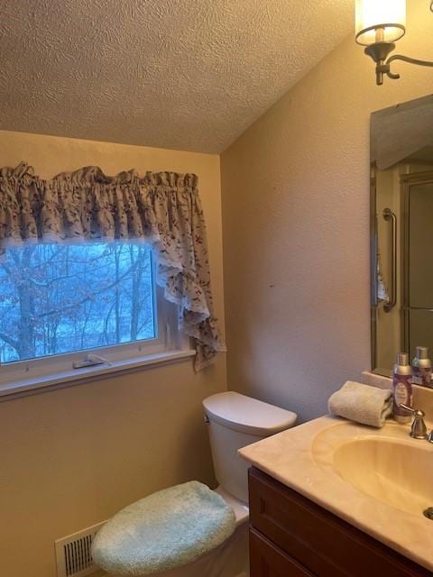 bathroom with visible vents, a textured ceiling, vanity, and toilet