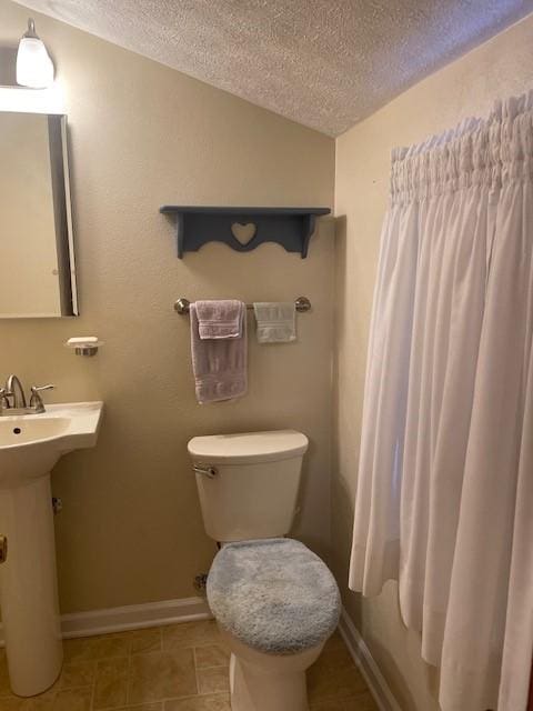 half bathroom with lofted ceiling, tile patterned floors, a textured ceiling, and toilet