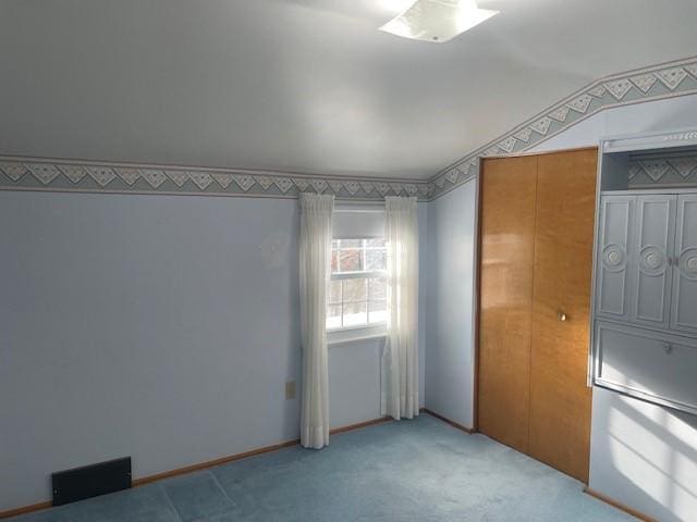 carpeted spare room featuring vaulted ceiling