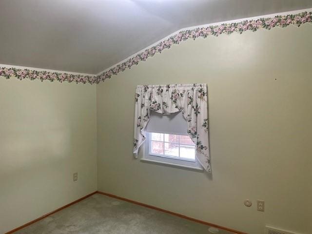 spare room featuring vaulted ceiling, baseboards, and light carpet