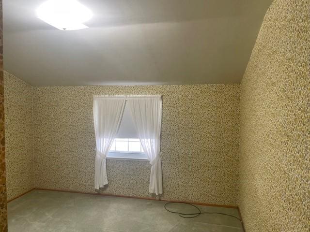 carpeted spare room with vaulted ceiling