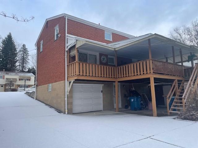 back of property with a garage, a carport, brick siding, and stairway