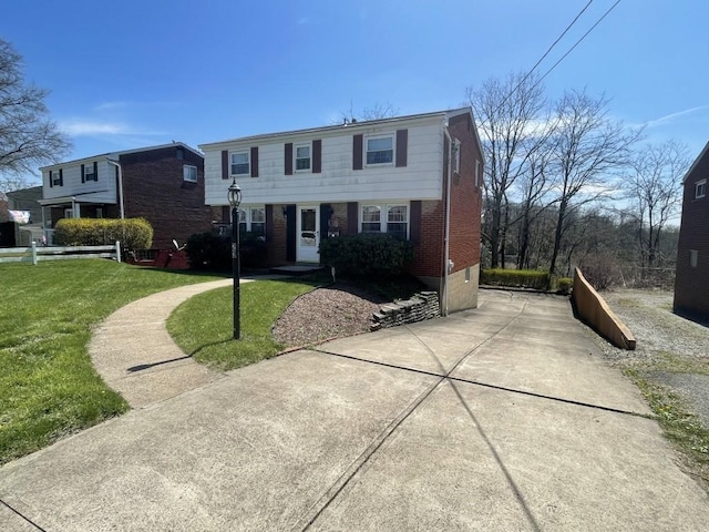 view of front of house with concrete driveway, brick siding, and a front yard