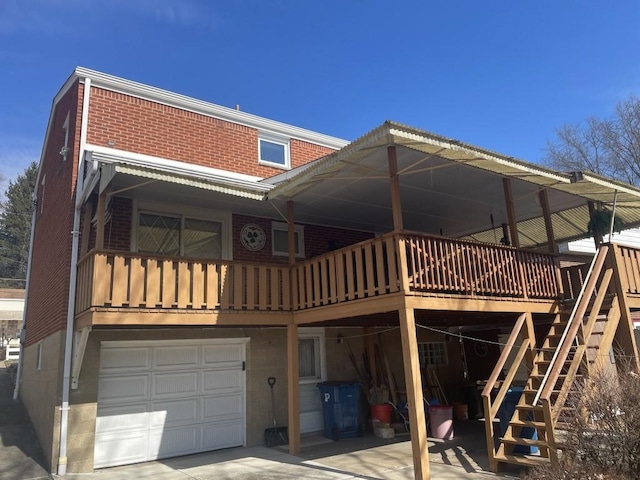 rear view of property with a garage, brick siding, a wooden deck, and stairs